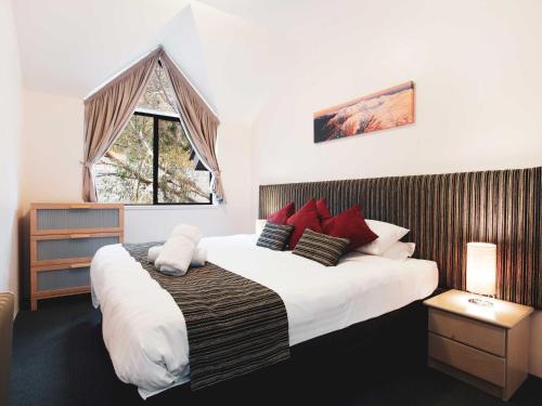 a bedroom with a large bed with red pillows at Lantern 1 Bedroom Loft with car space and Majestic View in Thredbo