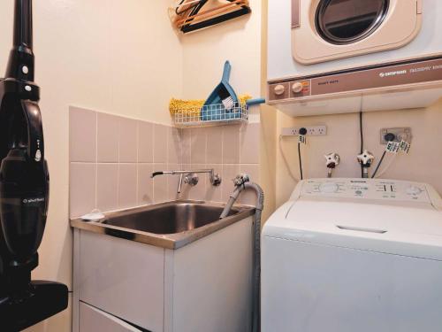 a small kitchen with a sink and a washing machine at Lantern 24 Balcony in Thredbo