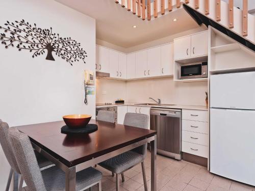 a kitchen with a wooden table and a white refrigerator at Lantern 1 Bedroom Loft with car space and Awesome View in Thredbo