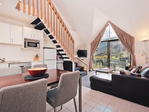 a kitchen and living room with a table and a staircase at Lantern 1 Bedroom Loft with car space and Awesome View in Thredbo