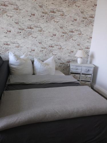a bed with white pillows and a brick wall at Pension Zur Alten Post in Havelberg