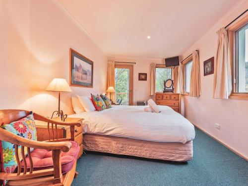 a bedroom with a bed and a chair at Lhotsky 2 Bedroom with fireplace and sweeping mountain view in Thredbo