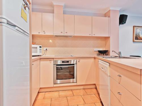 a kitchen with white cabinets and a sink and a refrigerator at Lhotsky 8 in Thredbo