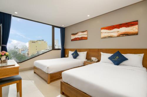 Una habitación de hotel con dos camas y una gran ventana. en CODI SEA Hotel & Travel, en Da Nang