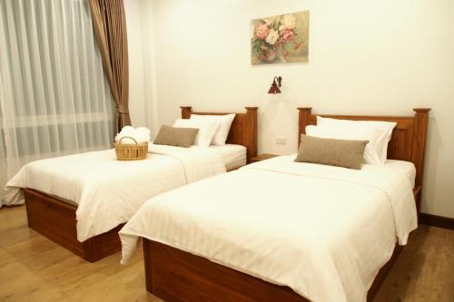 1 dormitorio con 2 camas con sábanas blancas en Romyen Cafe' Homestay, en Phra Nakhon Si Ayutthaya