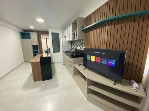 a living room with a flat screen tv and a kitchen at Maui Beach Residence in Tamandaré