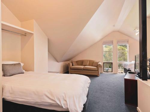 a bedroom with a large bed and a chair at Village Green 2 Bedroom loft townhouse with views fireplace and garage parking in Thredbo