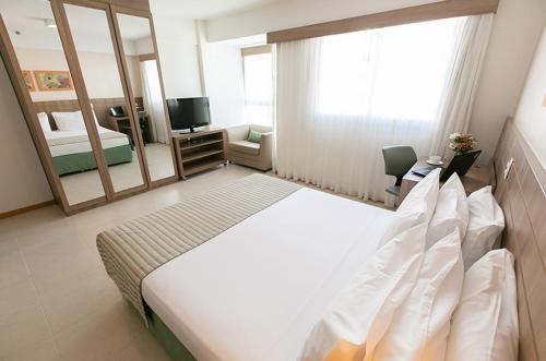 a hotel room with a large bed and a mirror at Flat Saint Moritz - Centro de Brasília A319 in Brasilia