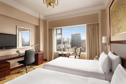 a hotel room with two beds and a desk and a window at Shangri-La Wuhan,Close to The Mixc with three subway lines in Wuhan