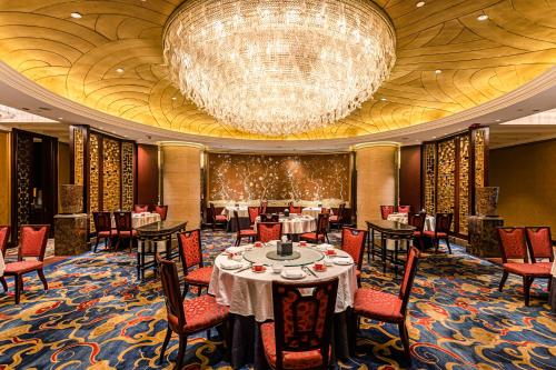 a dining room with a chandelier and tables and chairs at Shangri-La Wuhan,Close to The Mixc with three subway lines in Wuhan