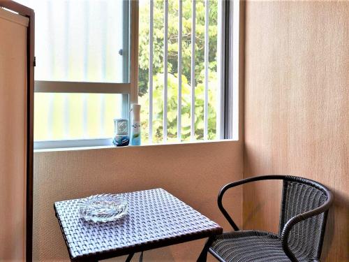 a table and a chair in front of a window at 民宿さざんか in Okinawa City