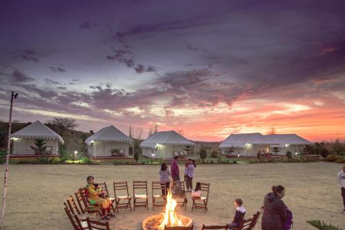 a group of people standing around a fire in front of tents at Pushkar Adventure Camp And Camel Safari in Pushkar