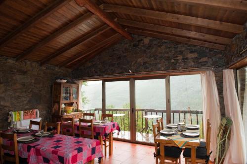 a dining room with a table and chairs and a large window at Talasnal Casa da Urze AL in Lousã