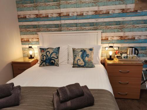 een slaapkamer met een wit bed en een houten muur bij THE QUORN HOTEL in Blackpool