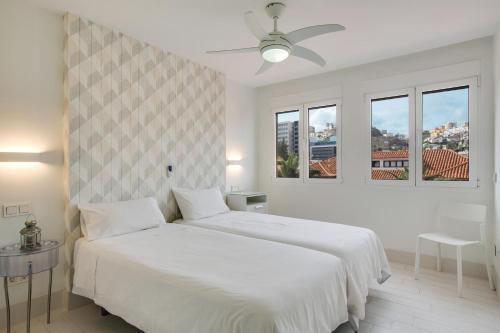 a white bedroom with a bed and two windows at Fantástico Apartamento cerca Playa in Las Palmas de Gran Canaria
