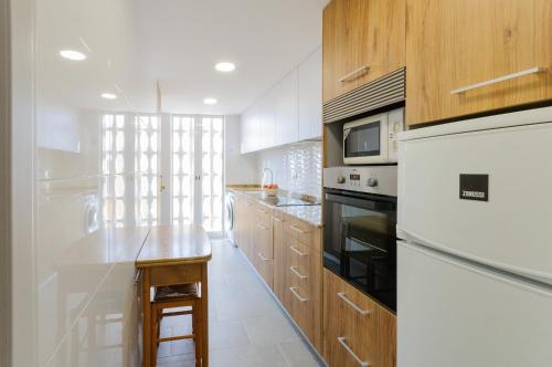 a kitchen with white appliances and wooden cabinets at Turia in Tavernes de Valldigna