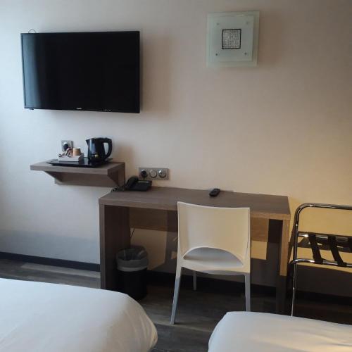 a hotel room with a desk with a television on the wall at The Originals City, Hôtel La Terrasse, Tours Nord in Tours