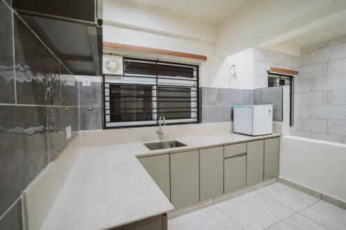 eine weiße Küche mit einem Waschbecken und einem Fenster in der Unterkunft Fortune Avenue in Mattanūr