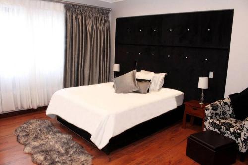 a bedroom with a large white bed with a black headboard at 4 Bedroom Luxury Home with View of the Ocean and Table Mountain in Cape Town