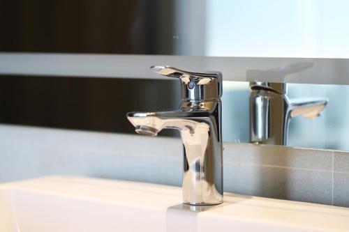 a bathroom sink with a chrome faucet in front of a mirror at The Signature Hotel Airport in Hat Yai