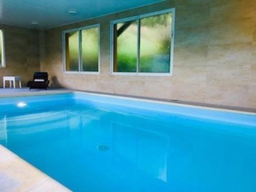 a large swimming pool with two windows in a room at Domaine Du Moulin Vallée Heureuse in Poligny
