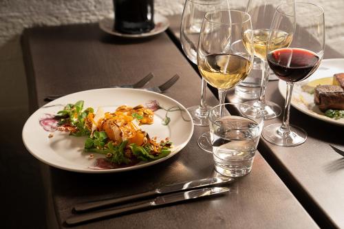 einen Tisch mit einem Teller mit Essen und Gläsern Wein in der Unterkunft Woikoski Feeling - WHD Gård in Nurmaa