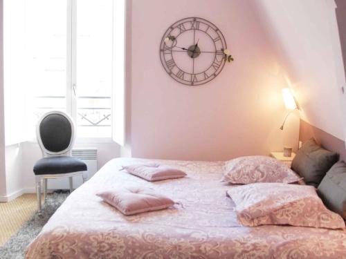 1 dormitorio con 1 cama y reloj en la pared en Maunoury Citybreak, en Chartres