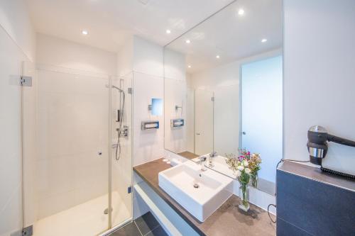 a white bathroom with a sink and a shower at Hotel Im Schulhaus in Lorch am Rhein