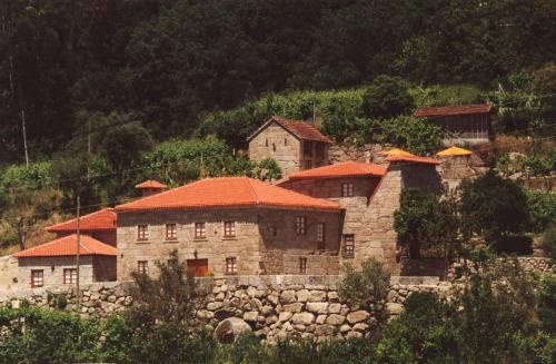 una vieja casa de piedra con techos rojos en una colina en Quinta da Várzea de Cima, en Marco de Canaveses