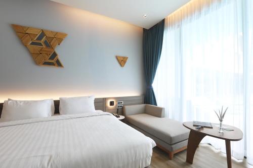 a bedroom with a white bed and a couch and a window at The Signature Hotel Airport in Hat Yai