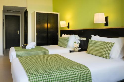 2 Betten in einem Hotelzimmer mit grünen Wänden in der Unterkunft htop BCN City #htopEnjoy in Barcelona