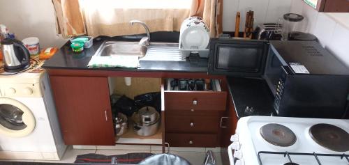 a small kitchen with a sink and a microwave at Kensington Luxury heights H107 in Kampala