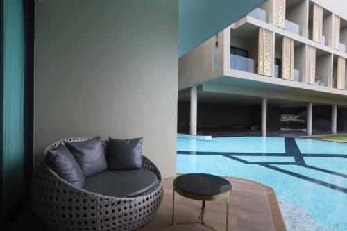 a wicker chair sitting next to a swimming pool at The Signature Hotel Airport in Hat Yai