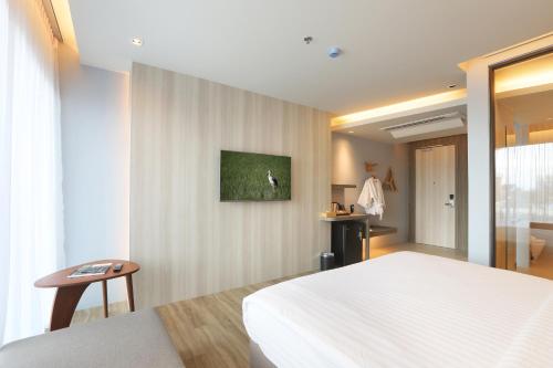 a bedroom with a white bed and a table at The Signature Hotel Airport in Hat Yai