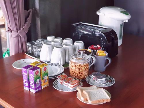 a table with plates of food and a coffee maker at Thaihome Resort in Ban Bang Muang