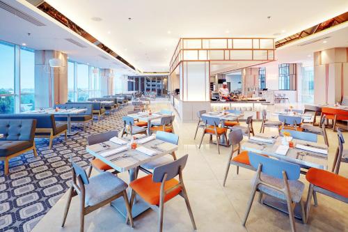 a restaurant with tables and chairs and a cafeteria at HARRIS Hotel & Conventions Bundaran Satelit Surabaya in Surabaya