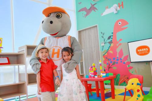 two children standing next to a teddy bear in a room at HARRIS Hotel & Conventions Bundaran Satelit Surabaya in Surabaya
