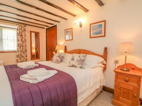 een slaapkamer met een groot bed en een paarse deken bij Stable Cottage in Colyton
