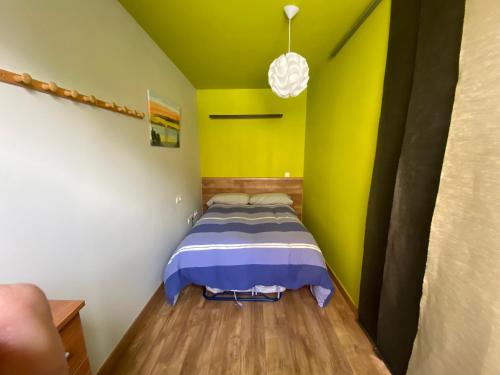 ein Schlafzimmer mit einem Bett mit gelber Wand in der Unterkunft Apartamentos San Isidro in León
