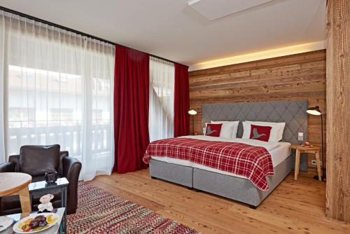 a hotel room with a bed and a chair at Das Achental Resort in Grassau