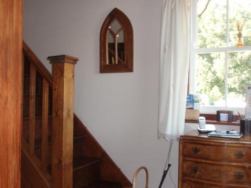 a room with a staircase and a dresser and a window at Meadow Farm Cottage in Norwich