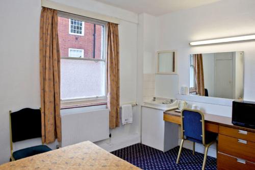 a hotel room with a bed, desk and a television at The County in London