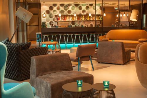 a lobby with chairs and tables and a bar at Motel One Berlin-Potsdamer Platz in Berlin