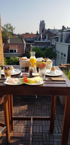 een houten tafel met eten en drinken op een balkon bij ZEN b&b in Dordrecht