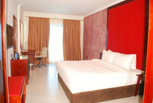 Habitación de hotel con cama y pared roja en Best Western Plus Atlantic Hotel, en Takoradi