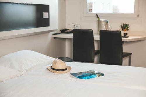 a hat sitting on a bed with two chairs at My Hotel Fribourg in Givisiez