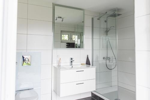 y baño blanco con lavabo y ducha. en Hüttenzauber im Naturpark Altmühltal, en Greding