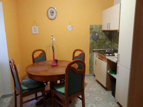 a kitchen with a wooden table with chairs and a kitchen at Apartmaji in sobe Kocjančič in Podčetrtek