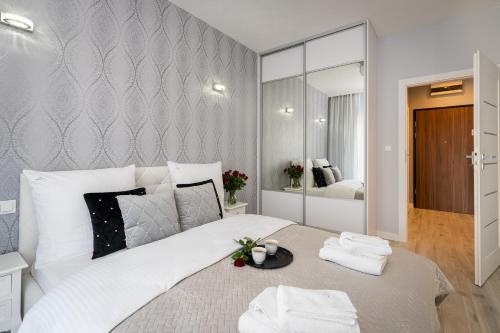 a bedroom with a large white bed and a mirror at Angel Apartments 1 in Krakow