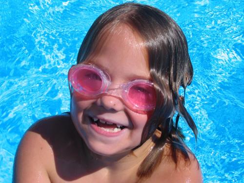 a young girl wearing a pair of goggles in a swimming pool at Apartmaji in sobe Kocjančič in Podčetrtek